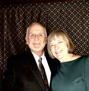 Bruce and Pam smile at the camera in formal wear.